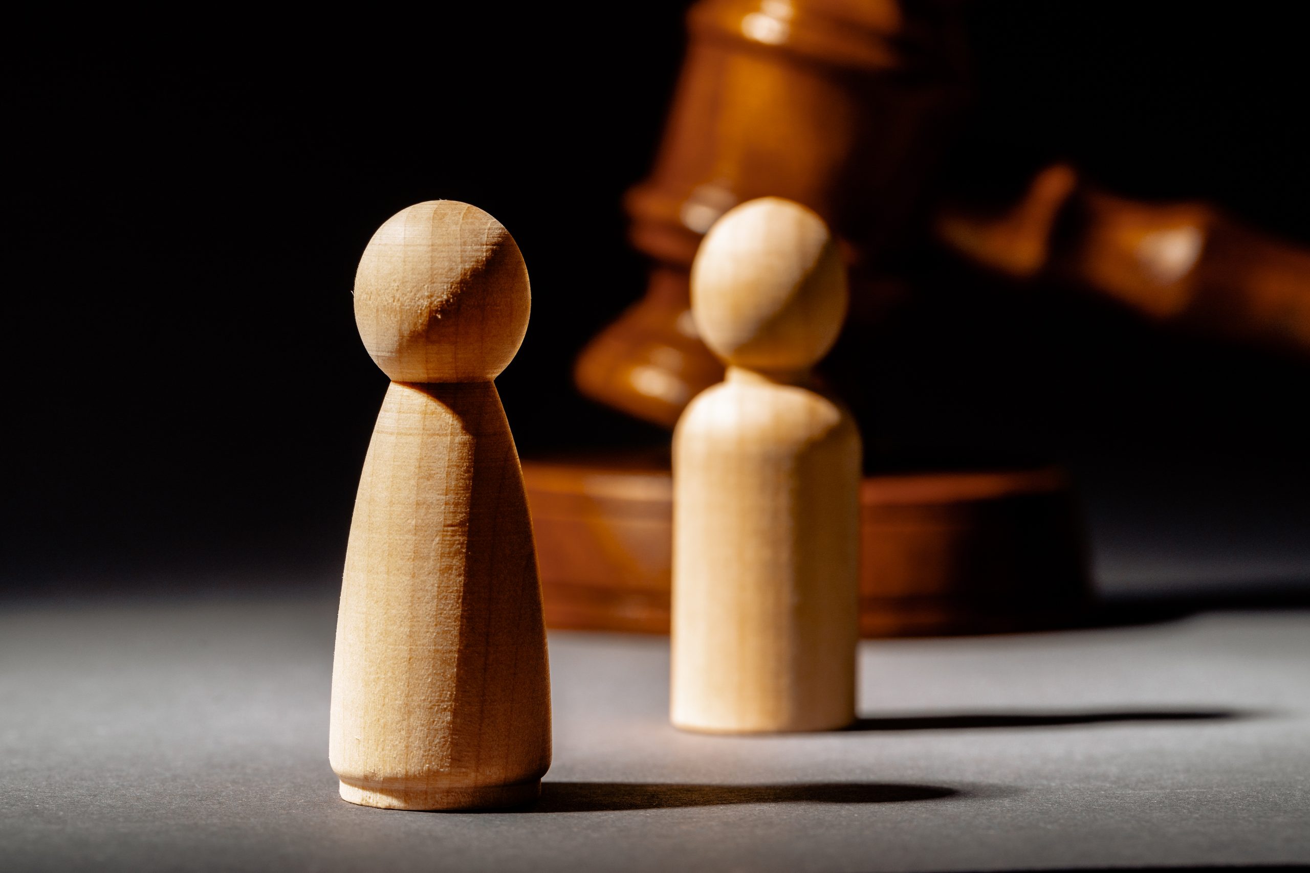 Le concept du divorce avec deux figurines en bois séparés par un marteau en bois de juge